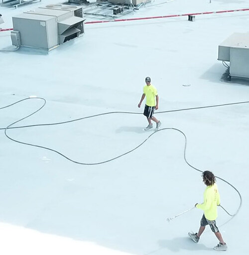 Roofers apply silicone coating.
