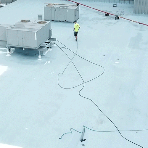Roofer applies roof coating.