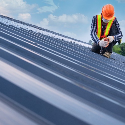 Roofer installs standing seam metal roofing.