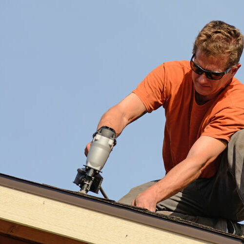 A roofer repairs asphalt shingles.
